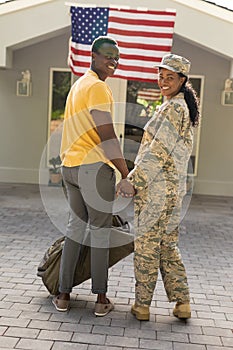 Portrait of smiling female mid adult african american soldier holding hand of husband on arrival