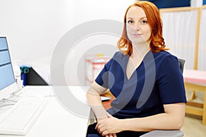 Portrait of a smiling female neurologist looking at camera in the office of a modern clinic. The neurology doctor is at work