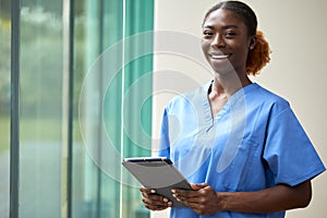 Portrait Of Smiling Female Nurse Or Doctor Wearing Scrubs With Digital Tablet