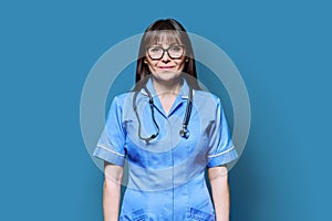 Portrait of smiling female nurse with stethoscope on blue background
