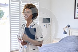 Portrait Of Smiling Female Nurse Wearing Uniform With Digital Tablet In Private Hospital Room