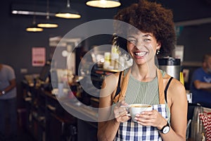 Portrait Of Smiling Female Owner Or Staff Inside Shop Or Cafe Holding Hot Drink