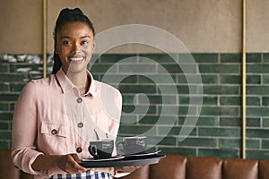 Portrait Of Smiling Female Owner Or Staff Member Carrying Cups In Cafe Or Coffee Shop