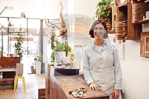 Portrait Of Smiling Female Sales Assistant Standing Behind Sales Desk Of Florists Store