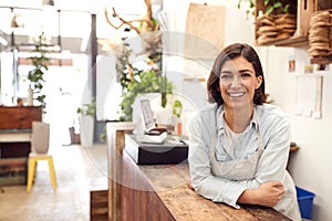 Portrait Of Smiling Female Sales Assistant Standing Behind Sales Desk Of Florists Store