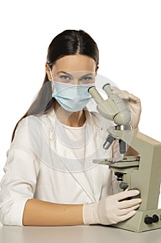 Portrait of smiling female scientist with microscope and face mask