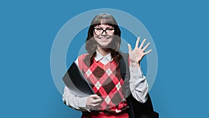 Portrait of smiling female student with laptop backpack, on blue background