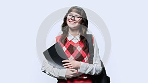 Portrait of smiling female student with laptop backpack, on light background