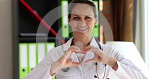 Portrait of smiling female therapist doctor showing finger heart sign