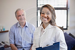 Portrait of smiling female therapist holding file with senior male patient