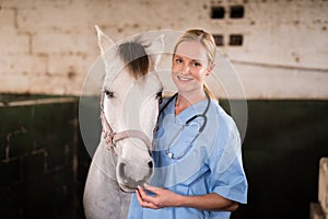 Portrait of smiling female vet standing by horse