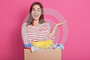 Retrato una mujer voluntario de pie más cercano regalos cabina contra rosas su mano sobre el página a mantiene boca 