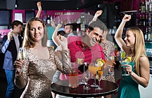 Portrait of smiling females and males having fun in the bar