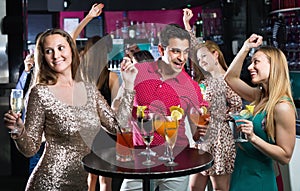 Portrait of smiling females and males having fun in the bar