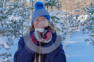 Portrait of smiling fit retired senior woman having tea after outdoor activity winter forest at snowy winter day. Active lifestyle