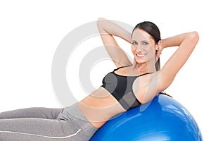 Portrait of a smiling fit woman stretching on fitness ball