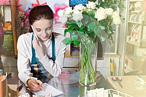 Portrait of smiling florist standing near the table with flowers