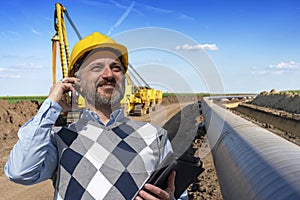 Portrait of Smiling Foreman With Mobile Phone At Gas Pipeline Construction Site