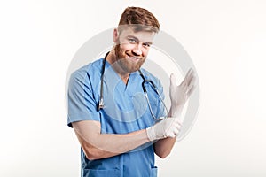 Portrait of a smiling friendly doctor putting on sterile gloves