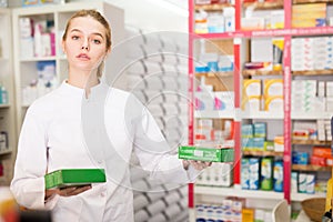 Portrait of smiling friendly female druggist in white coat working in pharmacy