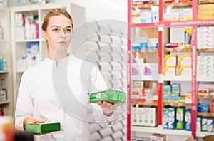 Portrait of smiling friendly female druggist in white coat working in pharmacy