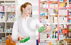 Portrait of smiling friendly female druggist in white coat working in pharmacy