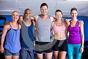 Portrait of smiling friends with arm around in gym