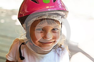 Portrait of a smiling girl 5 years in a pink bicycle helmet close-up on the street