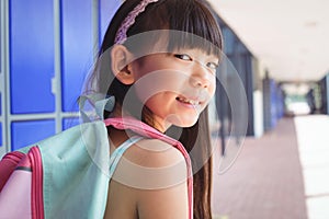 Portrait of smiling girl with backpack in corridor
