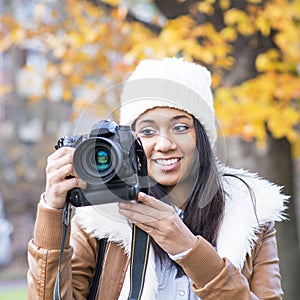 Portrait of smiling girl with bonnet and camera, autumn.