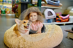 Portrait of smiling girl child with her loving corgi dog at pet shop