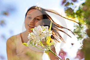 Portrait of smiling girl looking at a white flower with defocused background