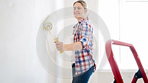 Portrait of smiling young girl painting walls with white paint