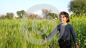 Portrait of smiling girl playing, Dancing and running on wheat field paths of dry grass in the sunset. Waving hands. Field on