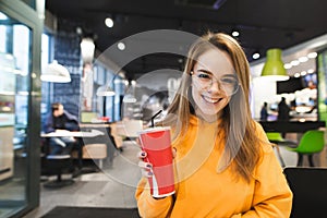 Portrait of smiling girl student with a glass of cool drink in hand