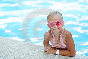 Portrait smiling girl in swimming pool, child in swimming glasses and inflatable sleeves. Summer travel hotel vacation