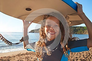 Portrait Of Smiling Girl Wearing Wetsuit Carrying Bodyboards On  Summer Beach Vacation