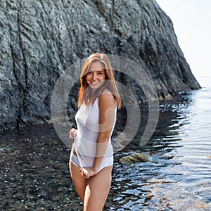 Portrait of smiling girl in white lingerie on rocky seashore