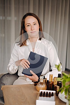 portrait of a smiling girl-woman sitting in an armchair. An aromatherapist in a white blouse is sitting in the office