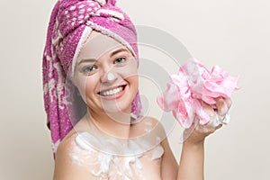Portrait of smiling girl woman with wet hair wrapped in pink towel taking shower or bath with foam and lather of soap