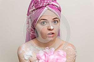 Portrait of smiling girl woman with wet hair wrapped in pink towel taking shower or bath with foam and lather of soap.