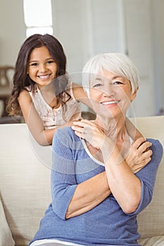 Portrait of smiling granddaughter embracing her grandmother in living room