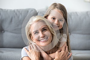 Portrait of smiling granddaughter piggyback grandmother at home
