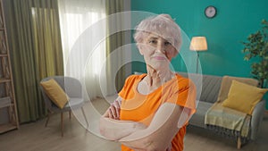 Portrait of a smiling grayhaired elderly woman with her arms crossed after a workout. Satisfied retired woman after home