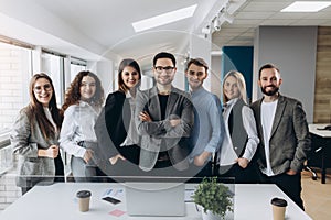 Portrait of a smiling group of diverse corporate colleagues standing in a row together in a bright modern office