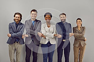 Portrait of a smiling group of diverse multiracial business people standing in a row holding hands.