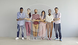 Portrait of a smiling group of diverse multiracial people standing in a row holding hands.