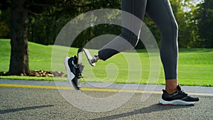 Smiling handicapped athlete jogging on road. Attractive girl running on in park