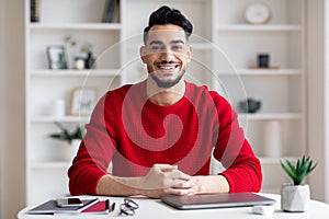 Portrait Of Smiling Handsome Arab Man Sitting At Desk In Home Office