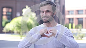 Portrait of Smiling Handsome Man Gesturing Heart with Hand
